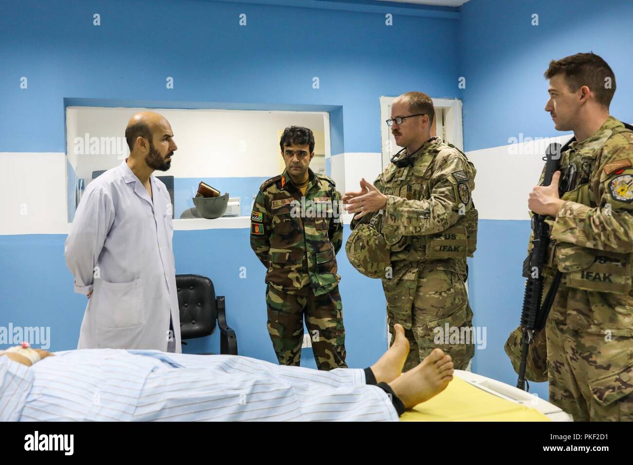 Der PROVINZ KANDAHAR, Afghanistan (5. August 2018) - U.S. Navy Leutnant Cdr. Justin S. Clark, Radiologie Techniker für Kandahar Airfield Rolle der NATO III Multinationale medizinische Einheit, spricht mit afghanischen in der Radiologie, 5. August 2018, während einer medizinischen Beratung Besuch bei Kandahar regionale militärische Krankenhaus, Camp Held in Kandahar, Afghanistan. Mitarbeiter aus der Rolle III Durchführung Routinemäßige Besuche auf KRMH zu trainieren und Beratung afghanischen medizinischen Personal. Stockfoto