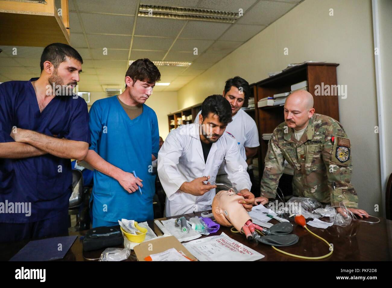 Der PROVINZ KANDAHAR, Afghanistan (5. August 2018) - U.S. Navy Leutnant Cdr. Travis J. Fitzpatrick, leitende Krankenschwester für Kandahar Airfield Rolle der NATO III Multinationale medizinische Einheit, beobachtet, wie Afghanischen Medizinischen Mitarbeiter demonstrieren, wie eine Fluglinie zu öffnen, 5. August 2018, während einer medizinischen Beratung Besuch bei Kandahar regionale militärische Krankenhaus, Camp Held in Kandahar, Afghanistan. Mitarbeiter aus der Rolle III Durchführung Routinemäßige Besuche auf KRMH zu trainieren und afghanischen medizinischen Personal beraten. Stockfoto