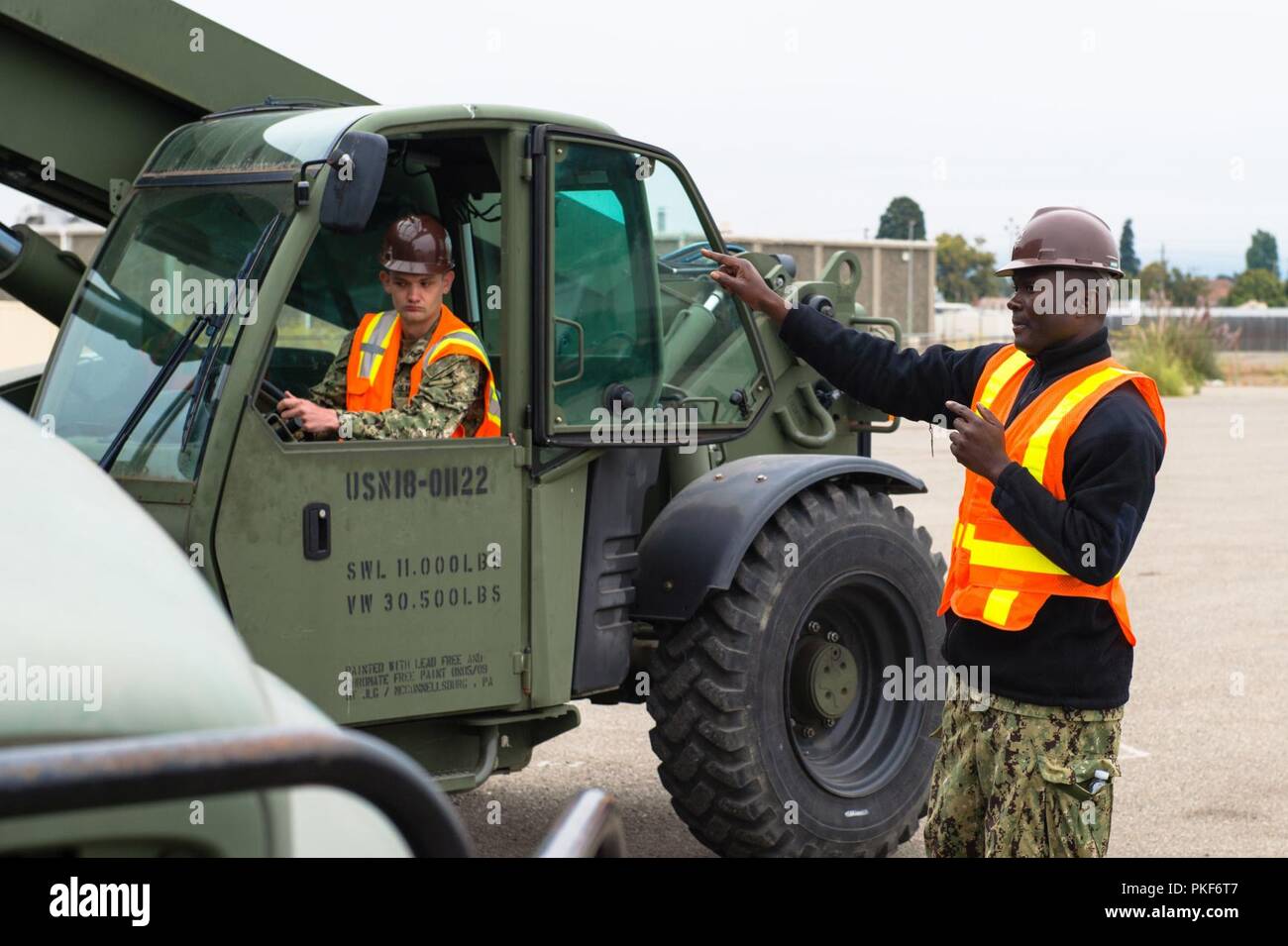 Calif (Aug. 8, 2018) Bootsmann Mate 3. Klasse Prosper Ahiakonu mit Marine Cargo Handling Bataillon (NCHB) 5 guides Constructionman Tyler Ruschetti mit NCHB 14 ein Container auf einen Lkw auf dem rangierbahnhof an der Alten Alameda Punkt während einer Übung zu liefern. NCHB NCHB 5 und 14 zwei-wöchigen regimental Übung bietet die Möglichkeit für Segler gemeinsam in einem Händen zu arbeiten - auf Umgebung, die umfassenden Qualifikationen, erhöhen die Bereitschaft und die Skillsets und Kenntnisse der Matrosen, die Bataillone zu entwickeln. Stockfoto