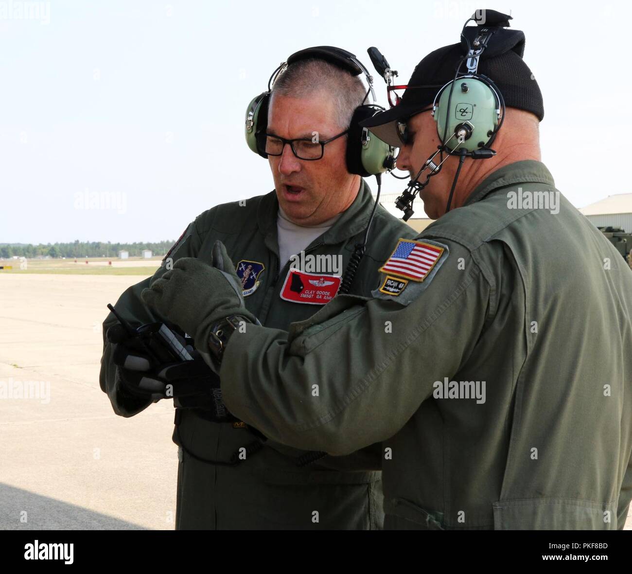 Senior Master Sgt. Ton gut, wer ist Teil der Besatzung mit dem 165 Airlift Wing, aus Savannah, Georgia, konferiert mit einem anderen Flieger über die Landung sie gerade auf Äschen Army Air Field am 8. August 2018 durchgeführt hatten. Die 165 Luftbrücke Flügel waren am Flugplatz in Grayling, Michigan helfen der 197th Field Artillery Brigade Headquarters, zentrale Batterie aus Manchester, New Hampshire, die Teilnehmenden in Northern Strike 18 dieses Jahr. Die Luftbrücke Flügel waren die Unterstützung der Feuerwehr durch sinnvolle Bewegung ihrer Haubitzen über schwieriges Gelände. Northern Strike Stockfoto