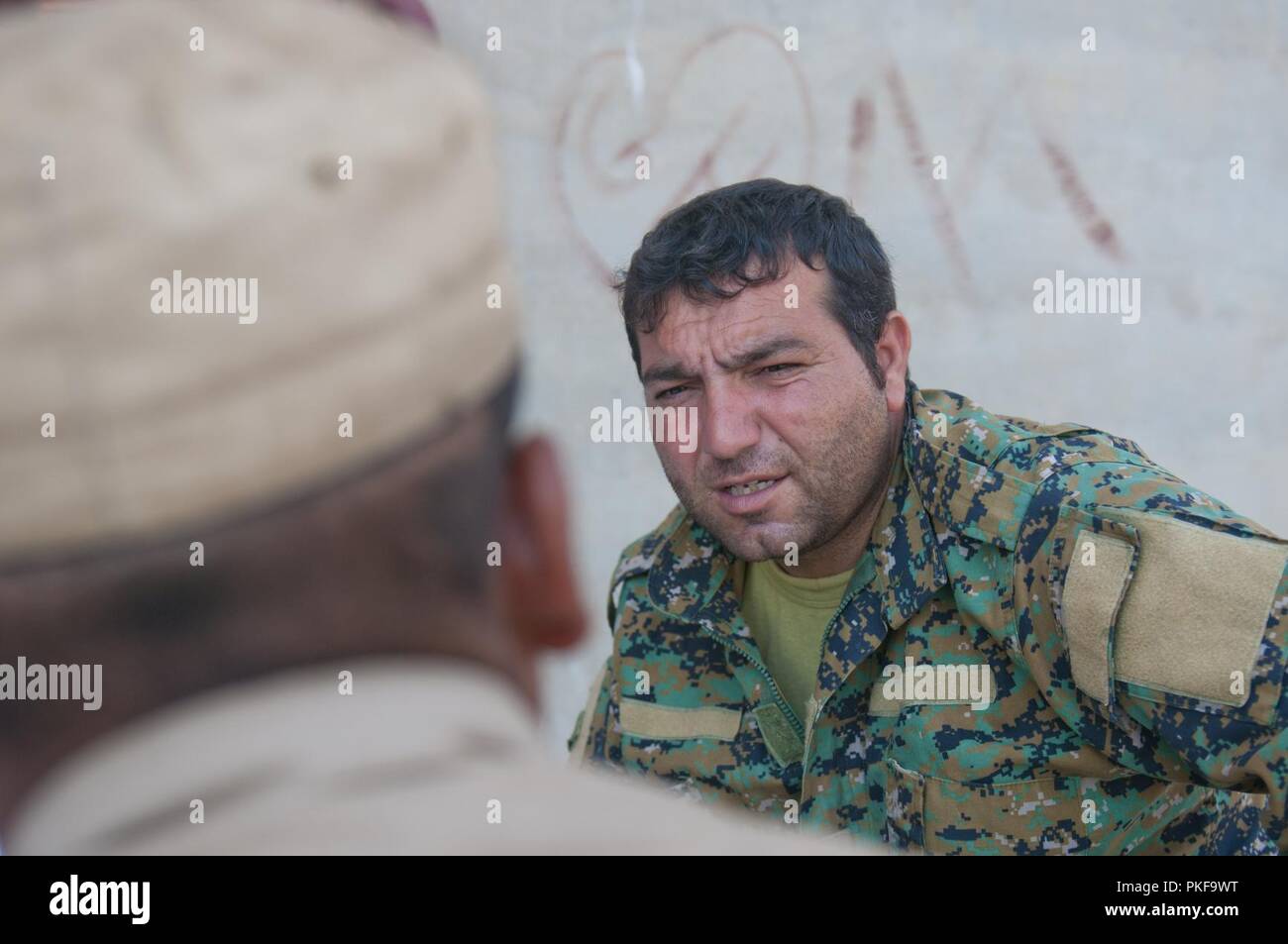 Eine syrische Demokratischen Kräfte Ausbilder fragen einen Praktikanten für das Screening in der Nähe von Shaddadi, Syrien, August 1, 2018 rekrutieren. Dies ist ein entscheidender Schritt im Einstellungsverfahren, um sicherzustellen, dass die Auszubildenden für die Aufgabe geeignet sind als die SDF-bereitet die endgültige ISIS Hochburg im nahen Fluss Euphrat Valley zu löschen. Stockfoto