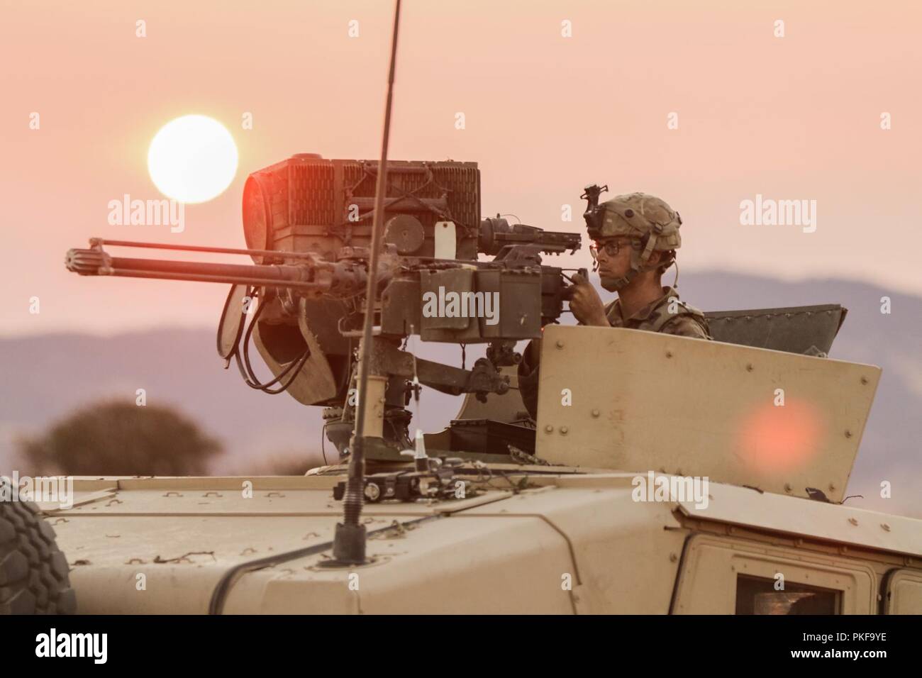 Bei Sonnenaufgang 7. August, ein M1151 Enhanced Armament Carrier HMMWV gunner aus der 1. Staffel 303rd Reiterregiment Scans sein Sektor Minuten vor einem gegnerischen Streitmacht Engagement im Bereich Ausbildung Übung der 41st Infantry Brigade Combat Team an exportierbar Combat Training (XCTC) 2018 im Fort Hunter Liggett, Kalifornien. Stockfoto