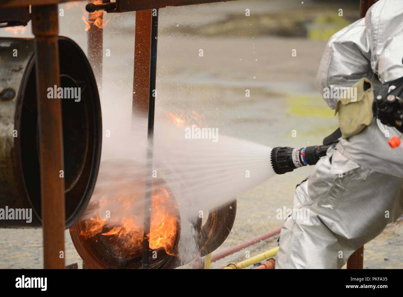 Der Küstenwache Sektor Columbia River Flugzeuge Rettung Brandbekämpfung Teammitglied verwendet Schlauch ein simuliertes Flugzeug ein Brand während einer Übung im Astoria Regional Airport, Erz, Aug 8, 2018 zu löschen. ARFF Teammitglieder bereit zu reagieren, ganzjährig, für alle Arten von militärischen und zivilen Flugzeugen Brände. Us-Küstenwache Stockfoto