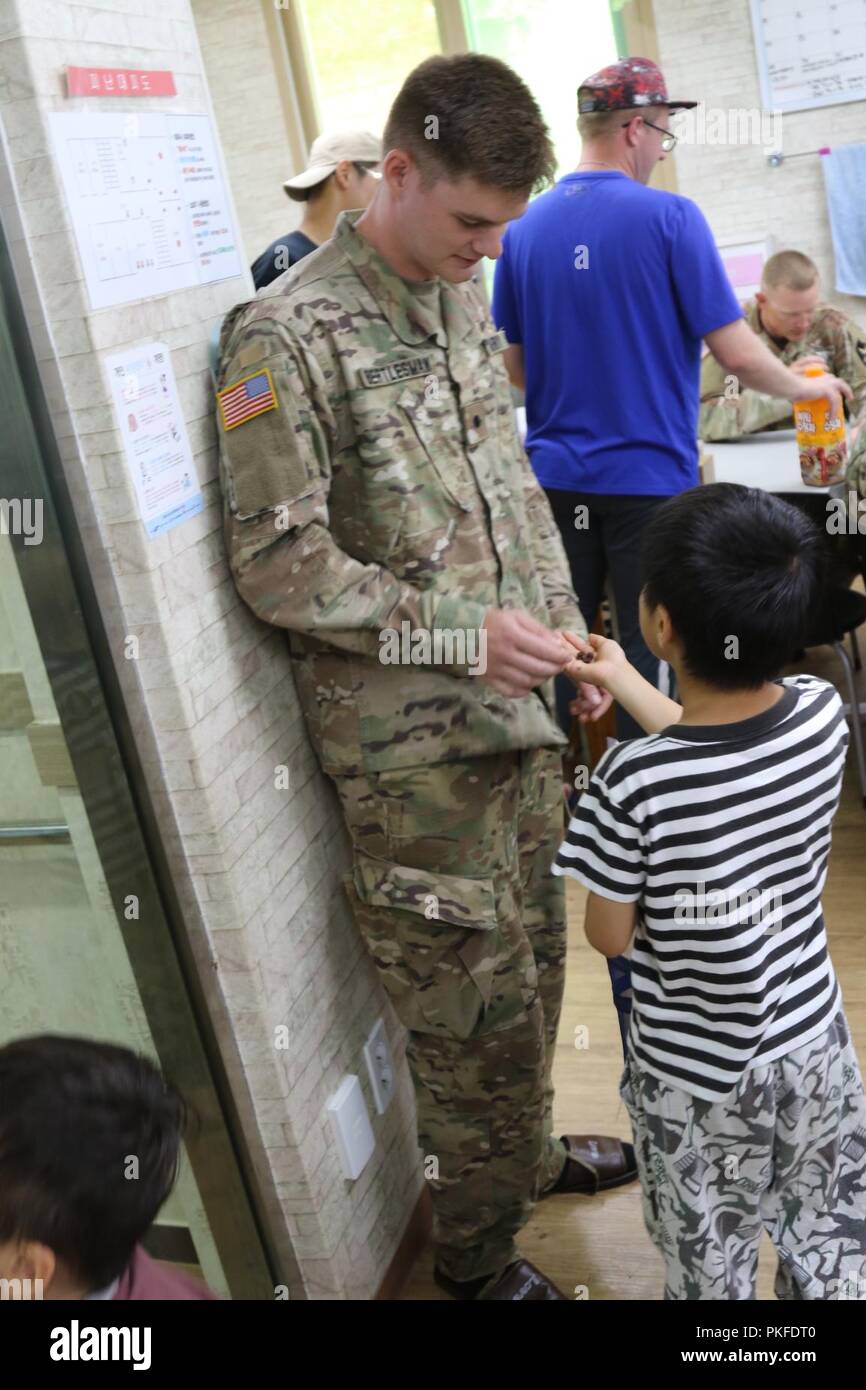 DONGDUCHEON, Republik Korea - Cadet Michael Bertlesman, ein steigender älterer Politische Wissenschaft an der Rochester Institut für Technologie von Plainview, New York, und Cadet Truppe Leadership Training" Teilnehmer in den 6 Battalion, 37th Field Artillery Regiment zugewiesen haben, akzeptiert eine Süßigkeit, die aus einer Student an ein Waisenhaus zum 31. Juli. Bertlesman begleitet sein Sponsor 2. Lt Seth Maddy, eine Brände Zugführer mit 6-37 Th. Soldaten an das Waisenhaus entfernt Ihre Schuhe und Sandalen trug wie in der Republik Korea üblich ist. Stockfoto