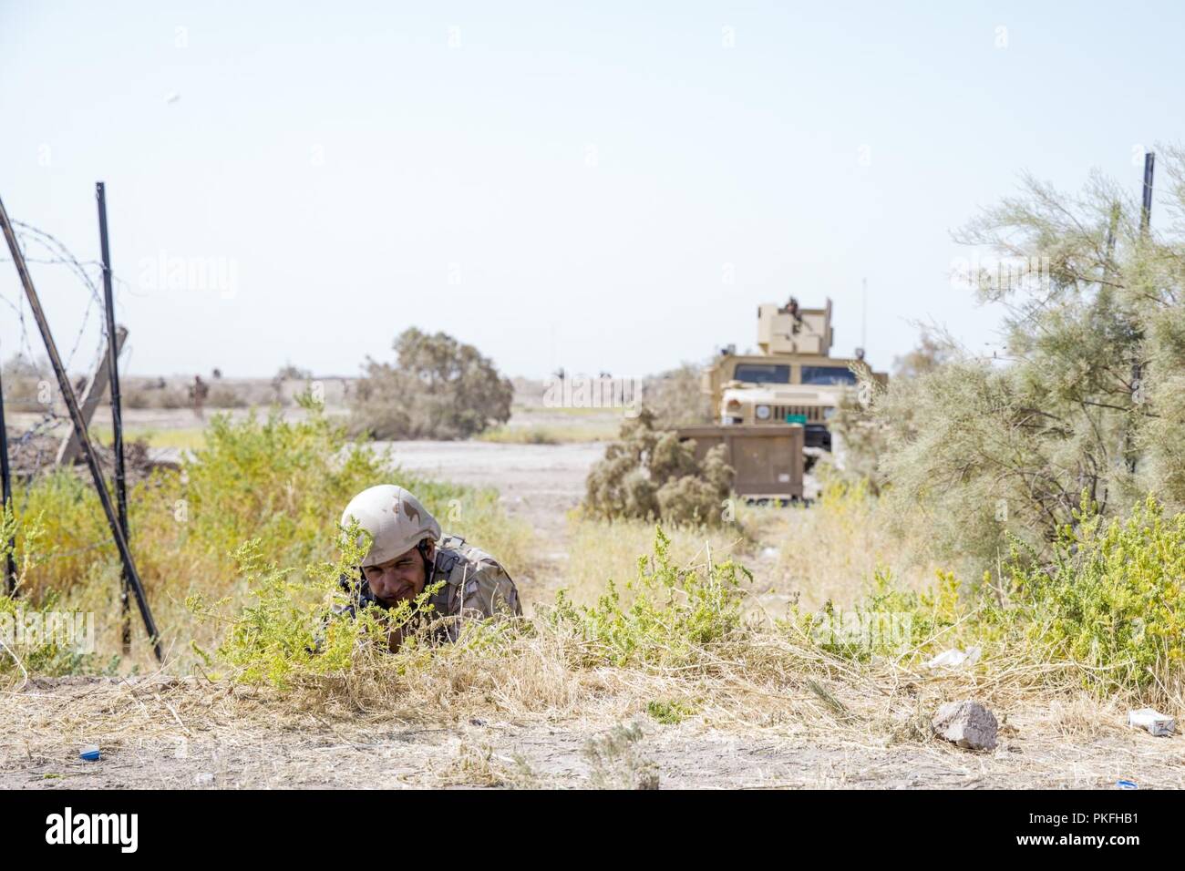 Ein irakischer Soldat, mit 2.BATAILLON 59th Brigade, nimmt Abdeckung während einer bestätigenden Aktivität, Probe im Camp Taji, Irak, 29. Juli 2018. Durch beschleunigte Erfolge gegen ISIS im Jahr 2017 aktiviert, Koalition Unterstützung für unsere Partner entwickelt, wie wir unsere Partner bei der Bereitstellung von Sicherheit, die Stabilisierung unterstützen. Stockfoto