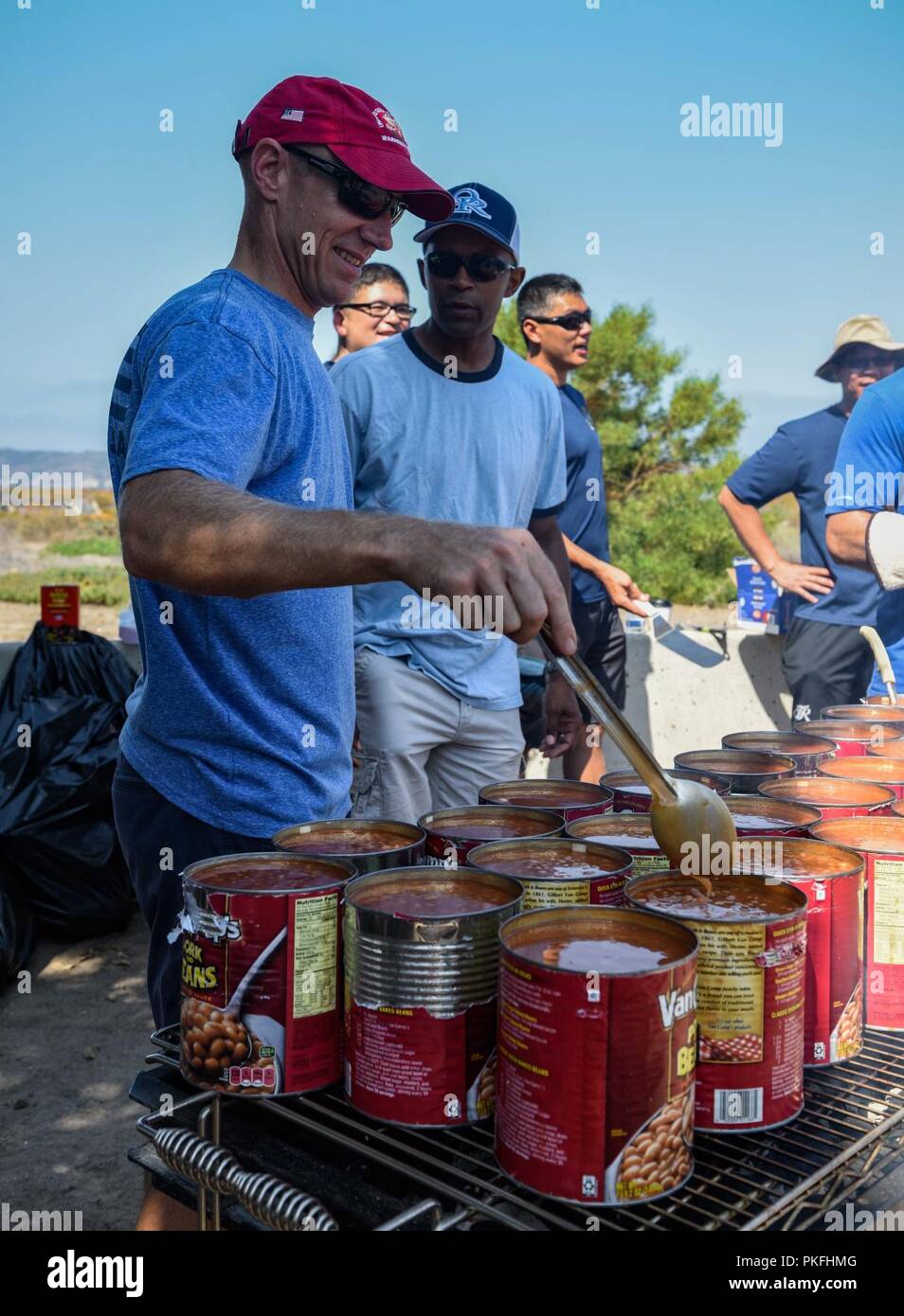 SAN DIEGO (3. August 2018) Kapitän Peter Riebe, Executive Officer der Flugzeugträger USS Theodore Roosevelt (CVN 71), rührt Bohnen während ein Befehl Picknick im Heritage Park auf die Naval Air Station North Island. Theodore Roosevelt ist derzeit in San Diego, die sich eine geplante geplante schrittweise Verfügbarkeit vertäut. Stockfoto