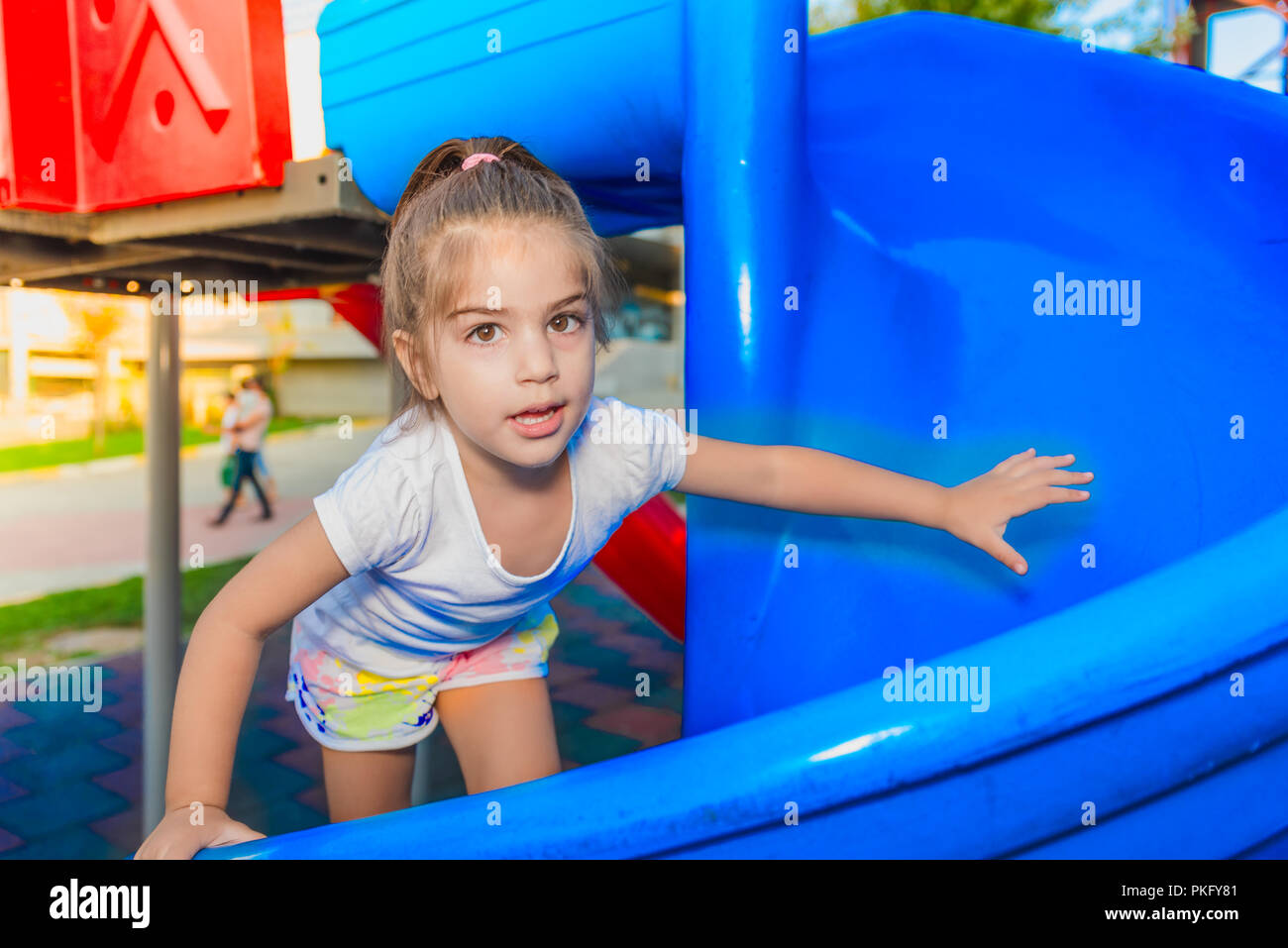 Portrait von niedlichen kleinen Mädchen halten und Klettern Schieberegler auf dem Spielplatz zu erreichen Stockfoto