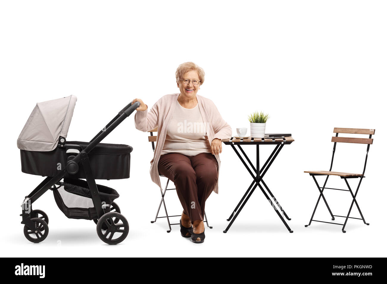Ältere Frau mit einem Kinderwagen an einem Kaffeetisch auf weißem Hintergrund sitzen Stockfoto