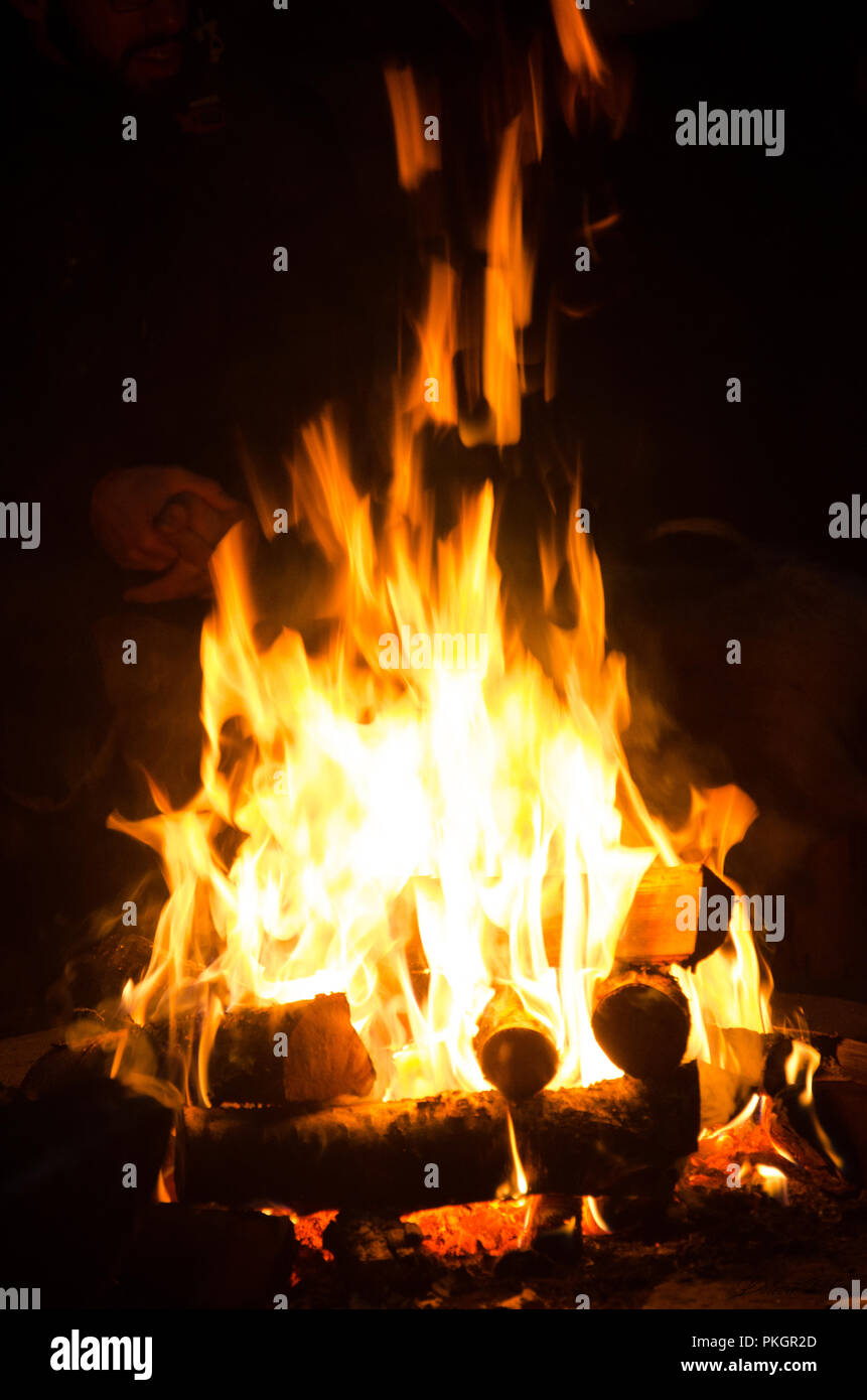 Das Verbrennen von Holz in der Nacht. Lagerfeuer an touristischen Camp an der Natur in den Bergen. Flamme amd Feuer Funken auf dunklen Abstrakt Hintergrund. Kochen Grill im Freien. Stockfoto