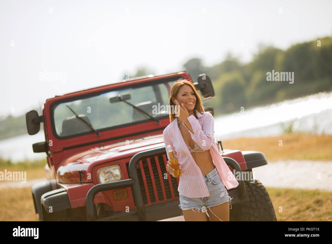 Junge Frau stand vor der Roten cabrio Auto in der Nähe des Flusses Stockfoto