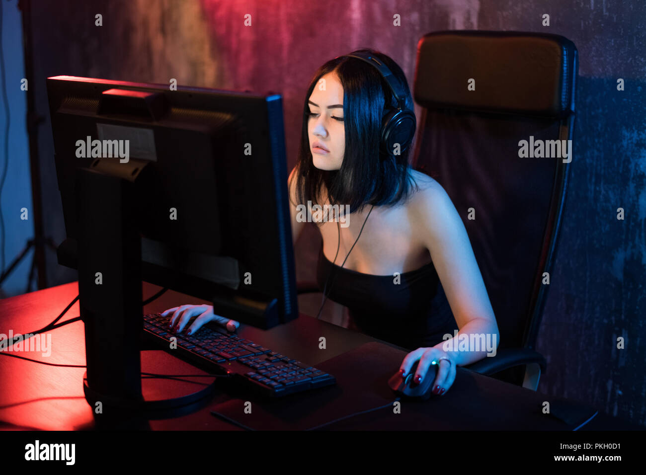 Schöne professionelle Gamer Mädchen spielen in First Person Shooter Online Video Spiel auf Ihrem eigenen Computer. Lässig süß Geek Brille und lächelnd. Cyber-e-Sport Internet Meisterschaft. Stockfoto