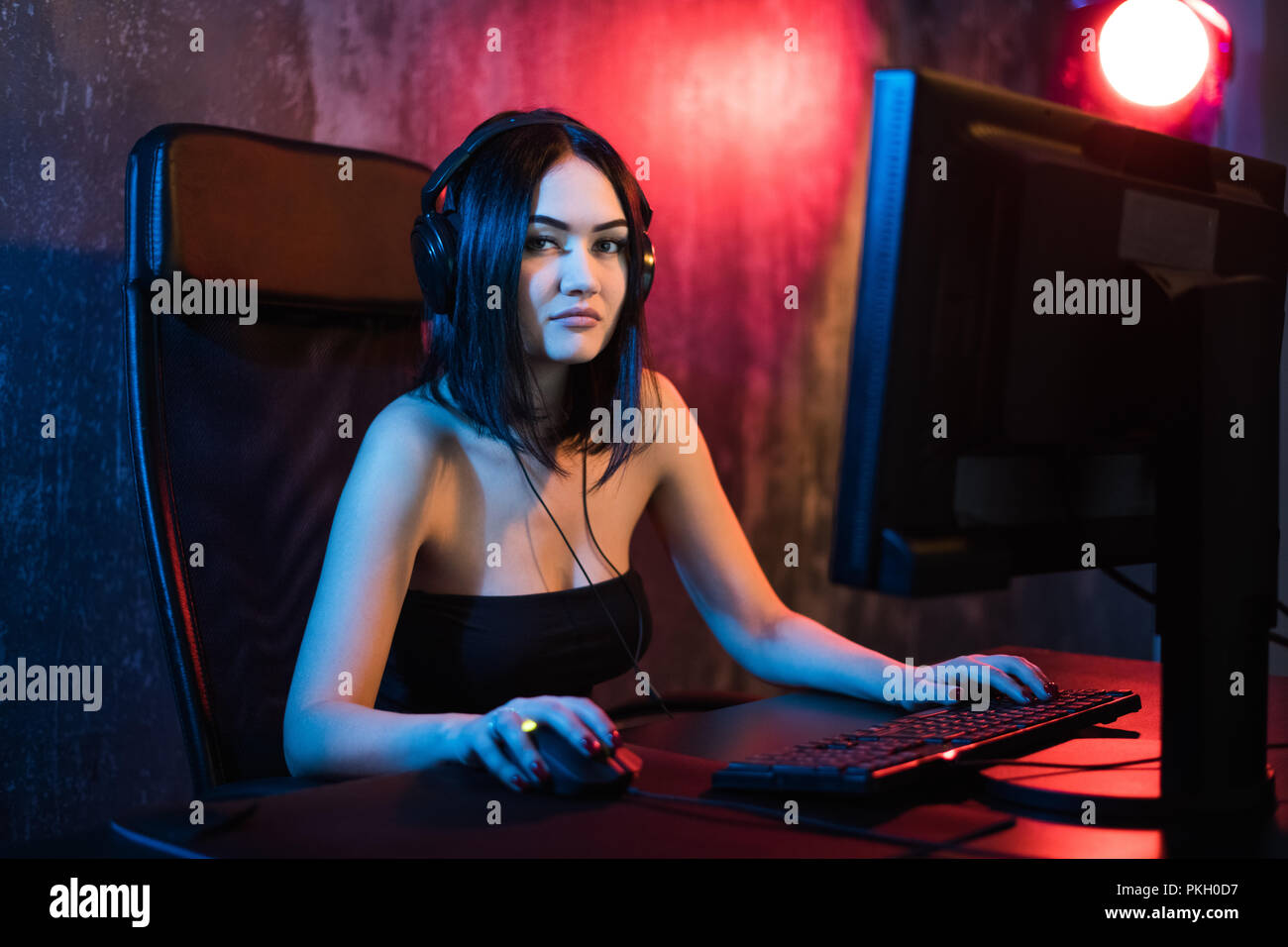Schöne professionelle Gamer Mädchen spielen in First Person Shooter Online Video Spiel auf Ihrem eigenen Computer. Lässig süß Geek Brille und lächelnd. Cyber-e-Sport Internet Meisterschaft. Stockfoto