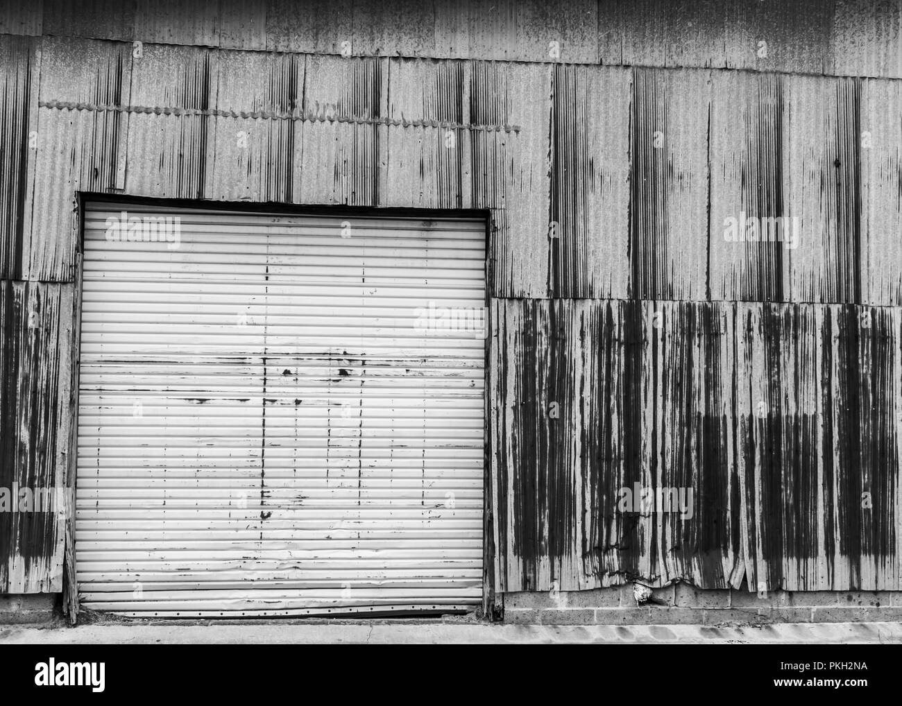Monochrome Garagentor auf eine verrostete Gebäude Stockfoto