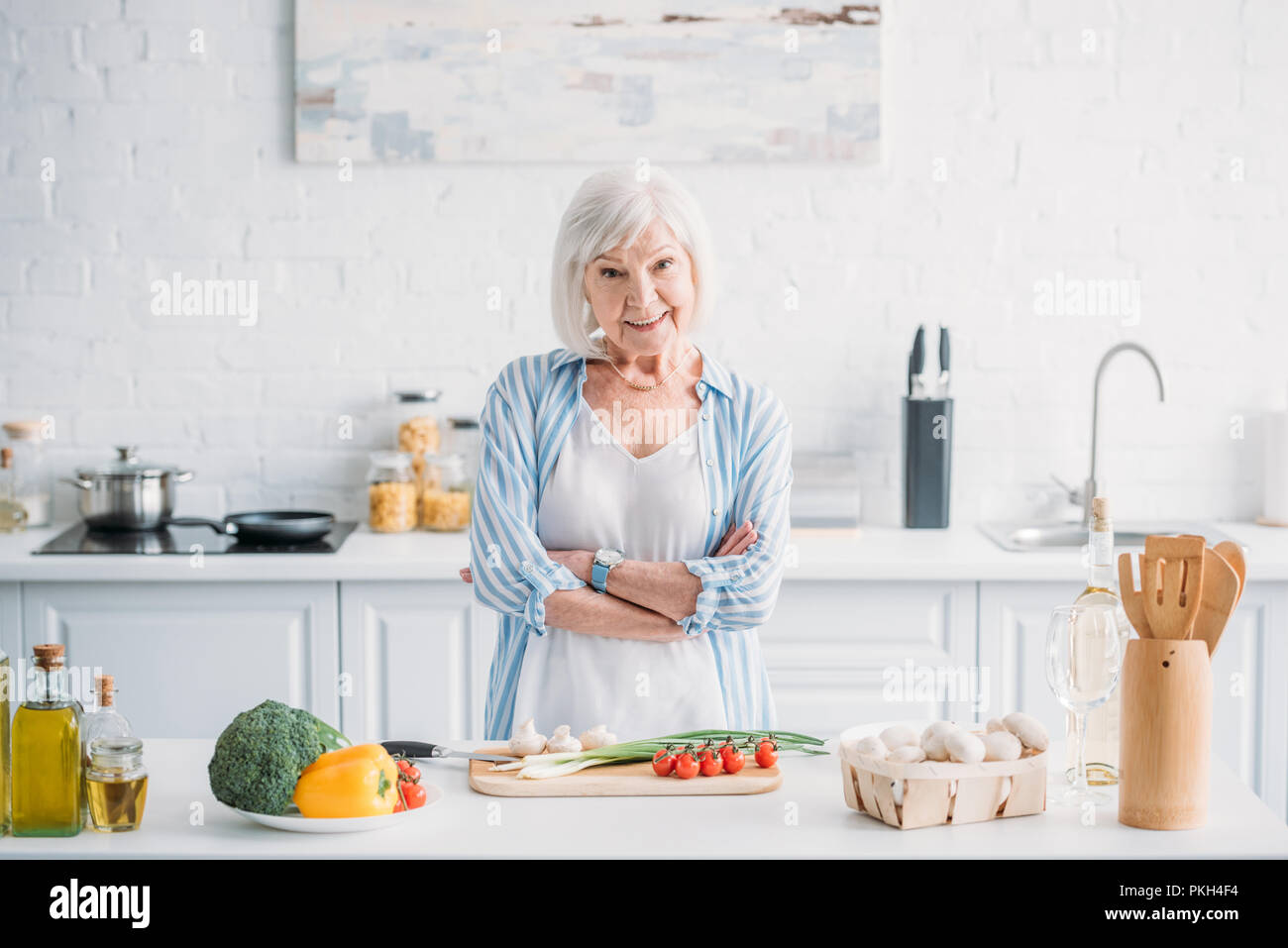 Portrait von lächelnden Senior mit gekreuzten Armen stehen an der Theke mit frischem Gemüse in der Küche Stockfoto