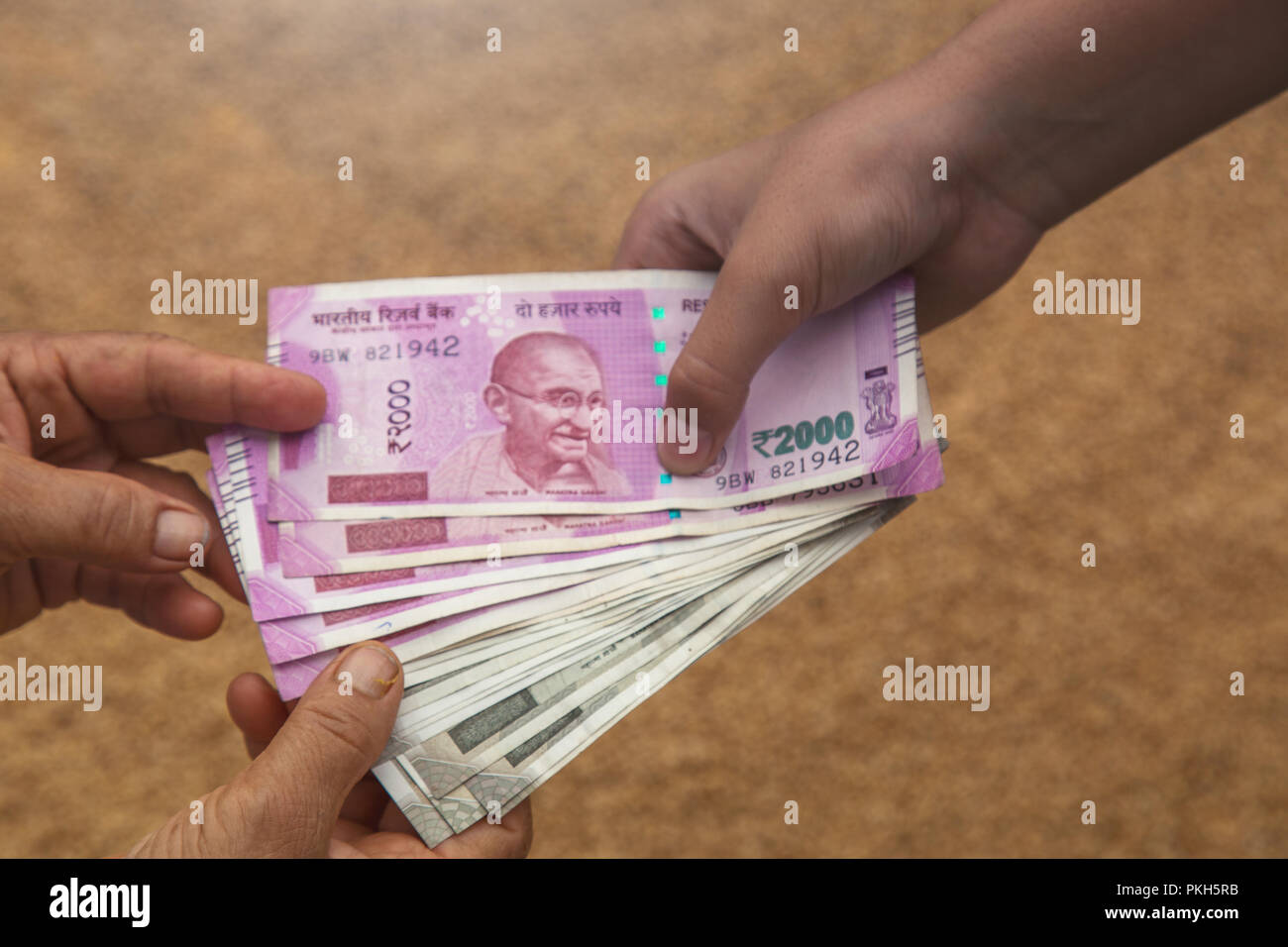 Hand geben Indische 500 und 2000 Rupien Banknoten über Weizen Hintergrund. Konzept für das Ergebnis oder verbringen Sie in der Landwirtschaft. Stockfoto