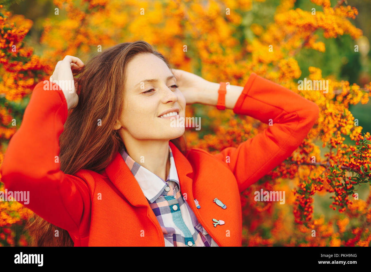 Portrait von wunderschönen natürlichen Mädchen mit langem gewelltem Haar, mit glücklichen Lächeln auf orange Beeren Hintergrund. Mädchen spielen mit Haar. Stockfoto