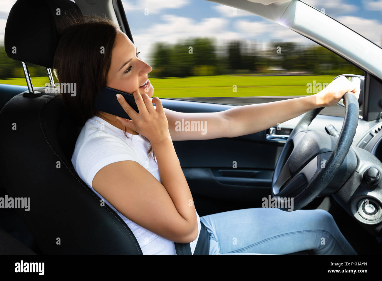 Seitenansicht einer schönen Frau mit Handy während der Fahrt Auto Stockfoto