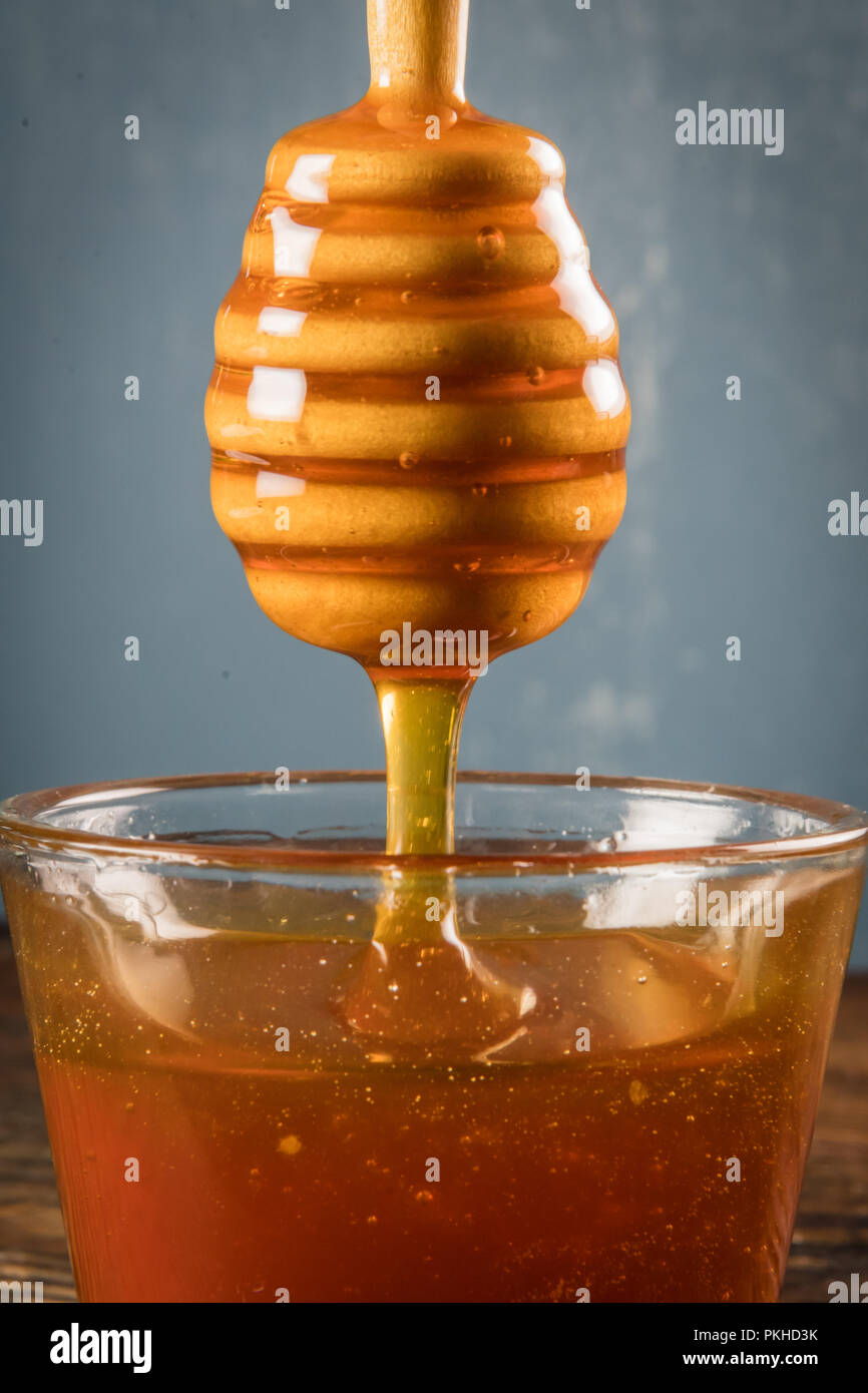 Honig fließt von der Spitze der Pendelarm in Honey Pot auf Holz Tisch Stockfoto