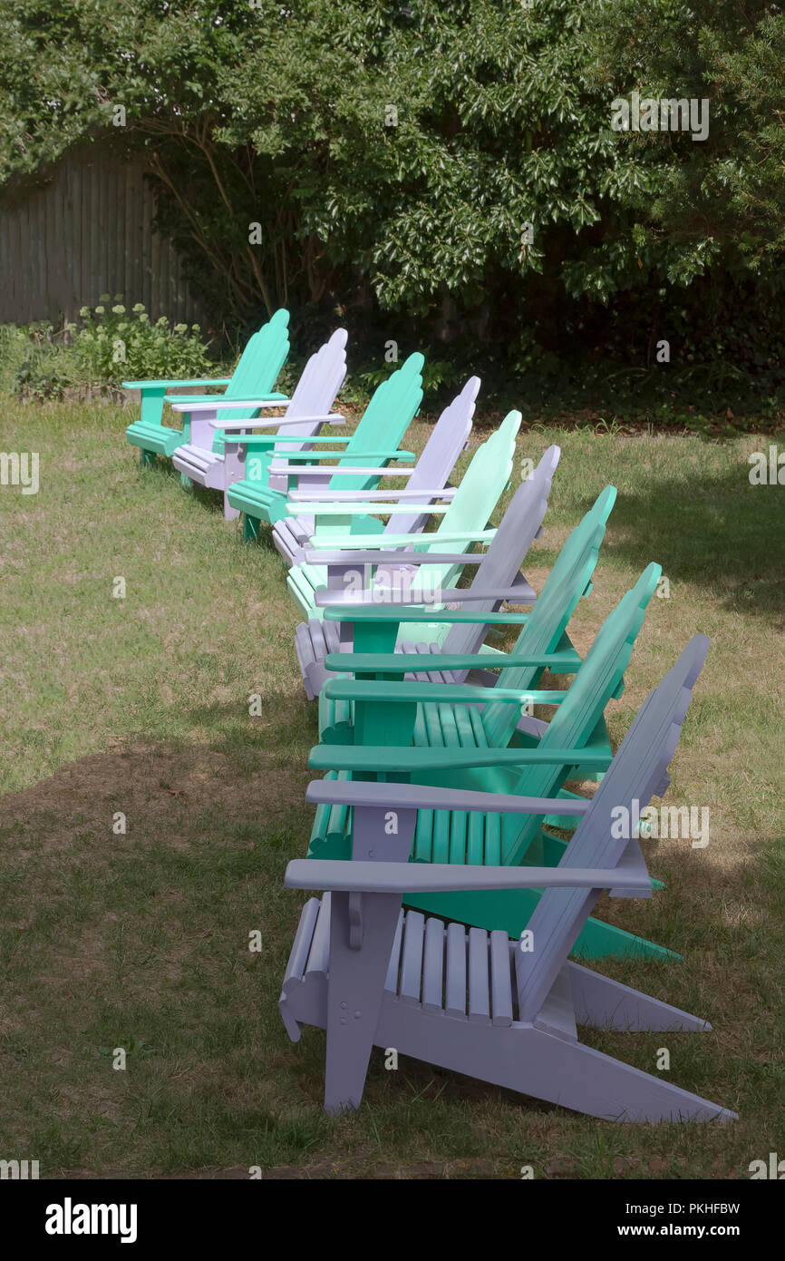 Reihe von Adirondack Stühle auf einem Rasen angeordnet. Stockfoto