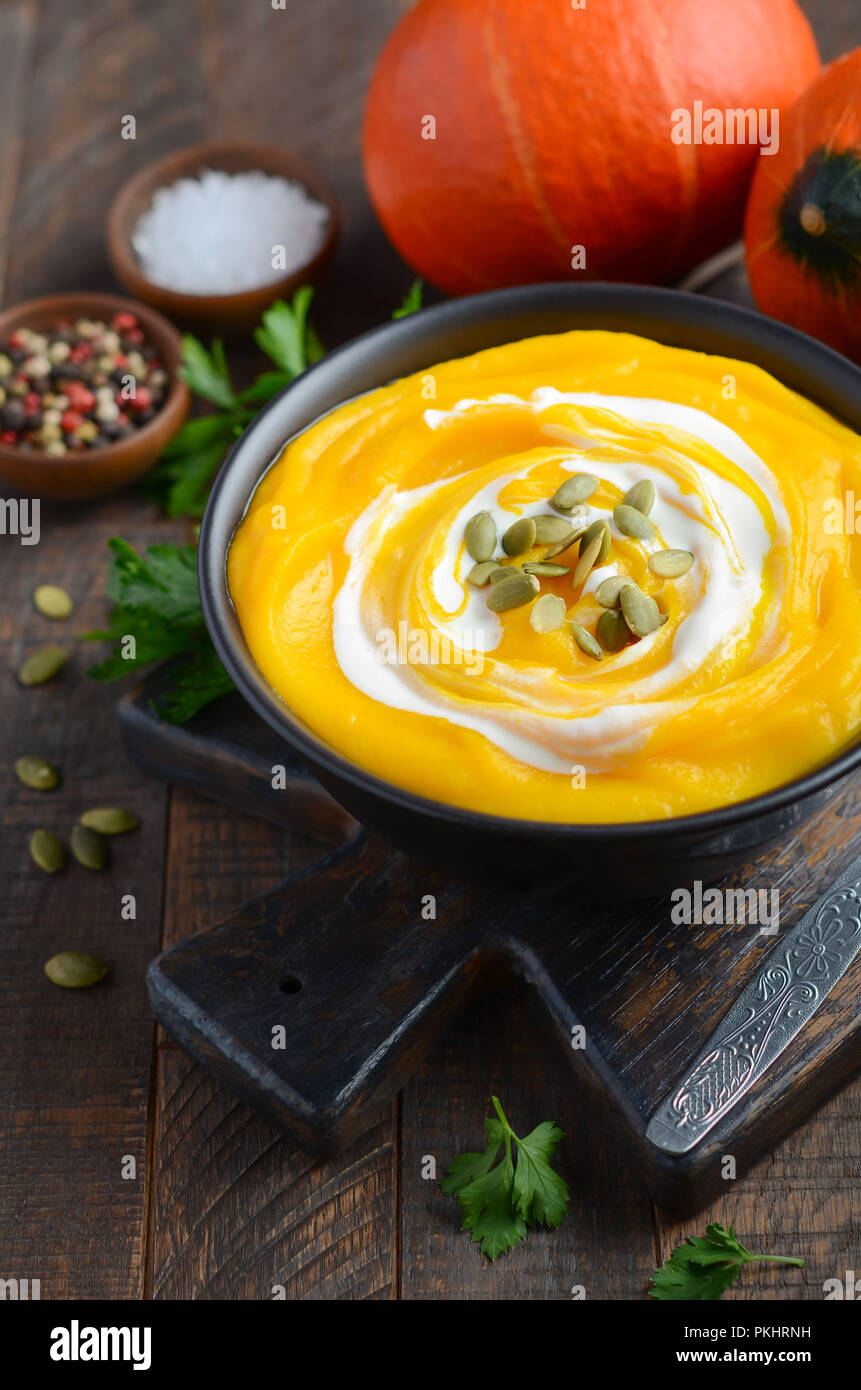 Kürbis Cremesuppe mit Sahne und Kürbiskerne auf rustikalen Holztisch. Stockfoto