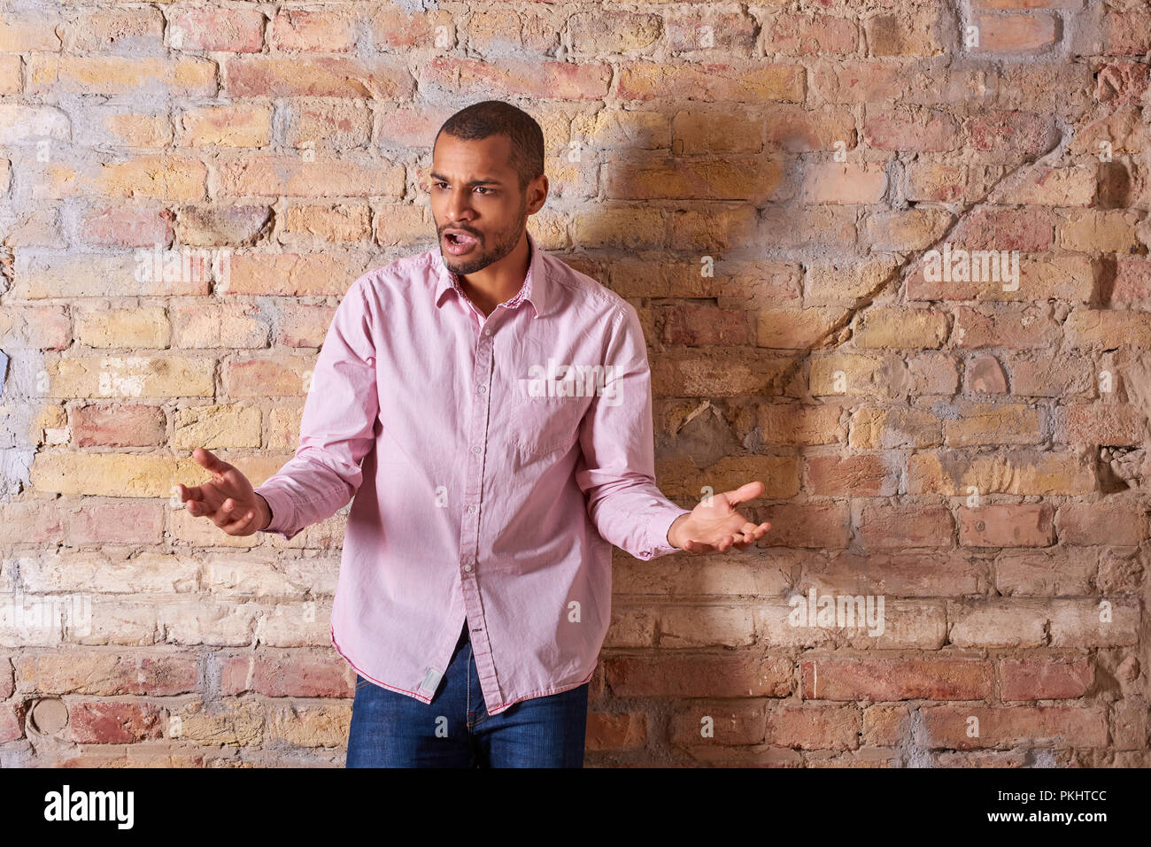 Porträt eines zornigen hübscher junger Mann, der in einem rosa Hemd. Stockfoto