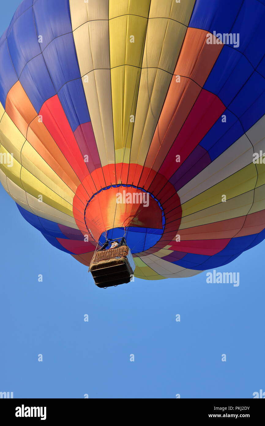 Großen bunten Heißluftballon in blauer Himmel, Korb mit Person innen, Blick von der Masse. Stockfoto