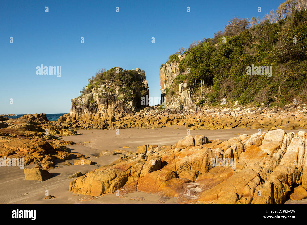 Australische Küstenlandschaft mit einsamen Sandstrand und Felsen unter blauen Himmel bei Diamond Head in Überfüllt Bay National Park NSW Stockfoto