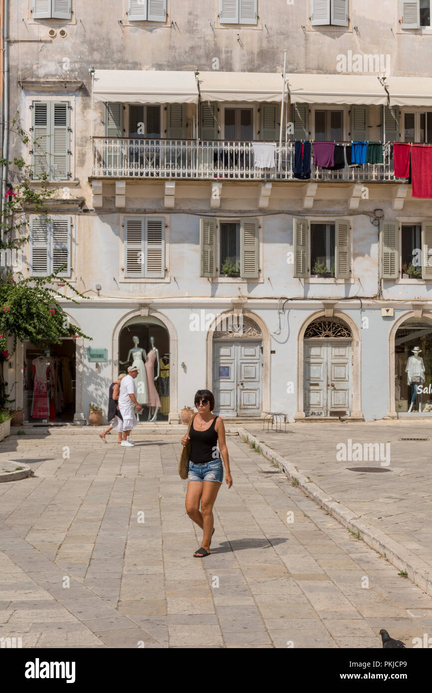 Attraktive junge Frau zu Fuß über eine typisch griechische Platz oder die Piazza mit Gebäuden und Balkone in Kerkyra, Korfu, Griechenland. Stockfoto