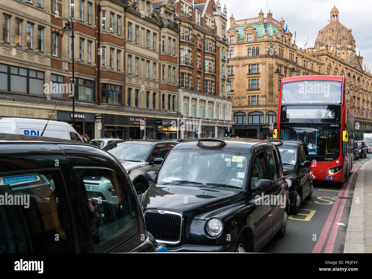 Die schwarzen Taxis auf der Brompton Road in Knightsbridge und Harrods im Hintergrund, London England United Kingdom UK Stockfoto