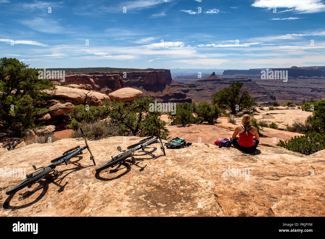 Eine Frau hält für eine Pause beim Reiten eines Mountainbike entlang einer Spur in Dead Horse Point State Park, Utah, USA. Stockfoto