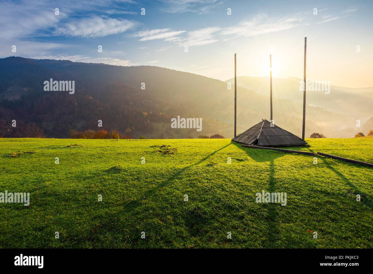 Leere Heu Baracke auf einem grasbewachsenen Hügel bei Sonnenaufgang. wunderschönen nebligen Landschaft, die in der fernen Tal. ländlichen Lebensstil Stockfoto