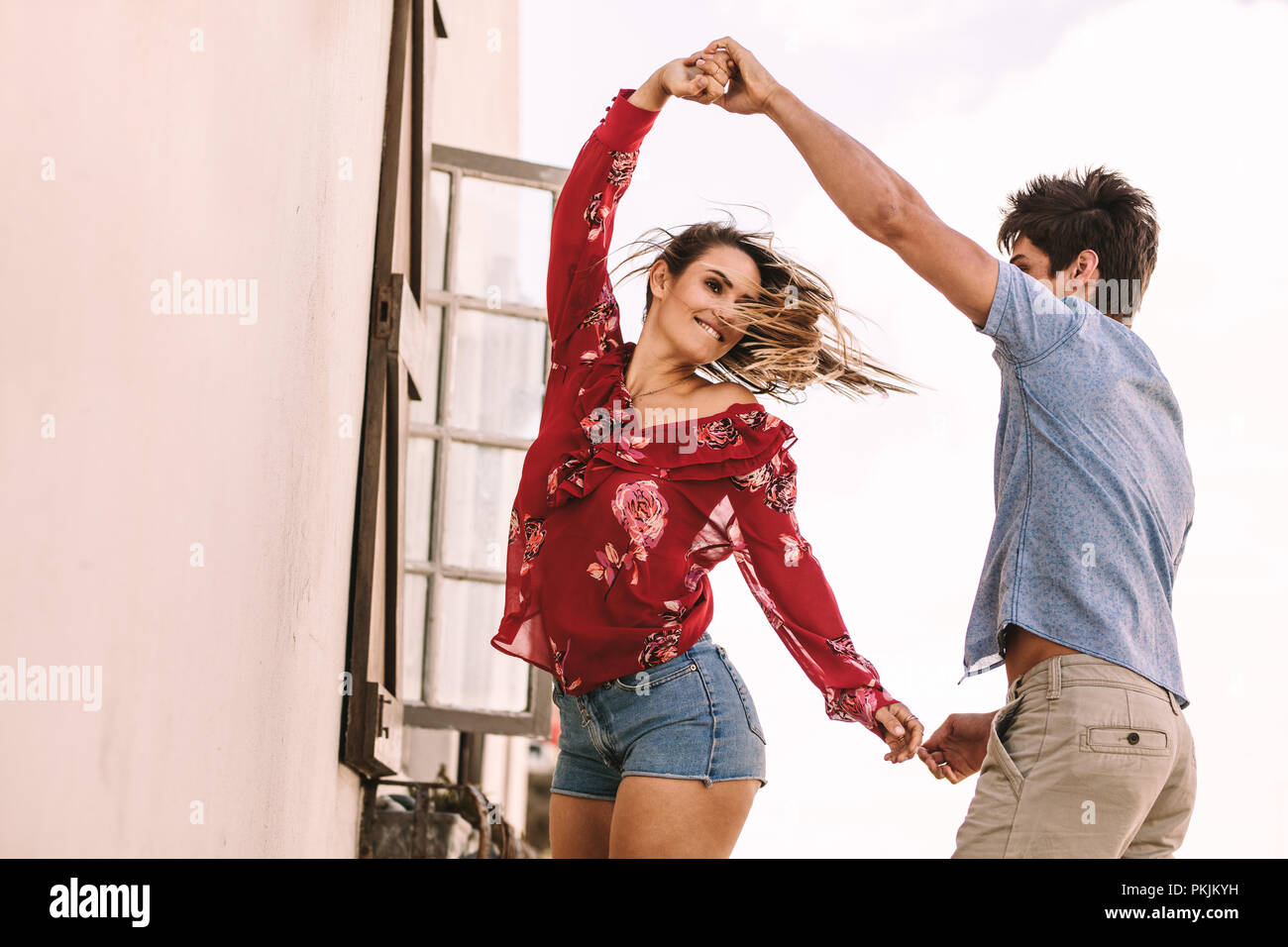 Paar tanzen im Freien halten sich an den Händen. Mann an der Hand seiner Freundin beim Tanzen. Stockfoto