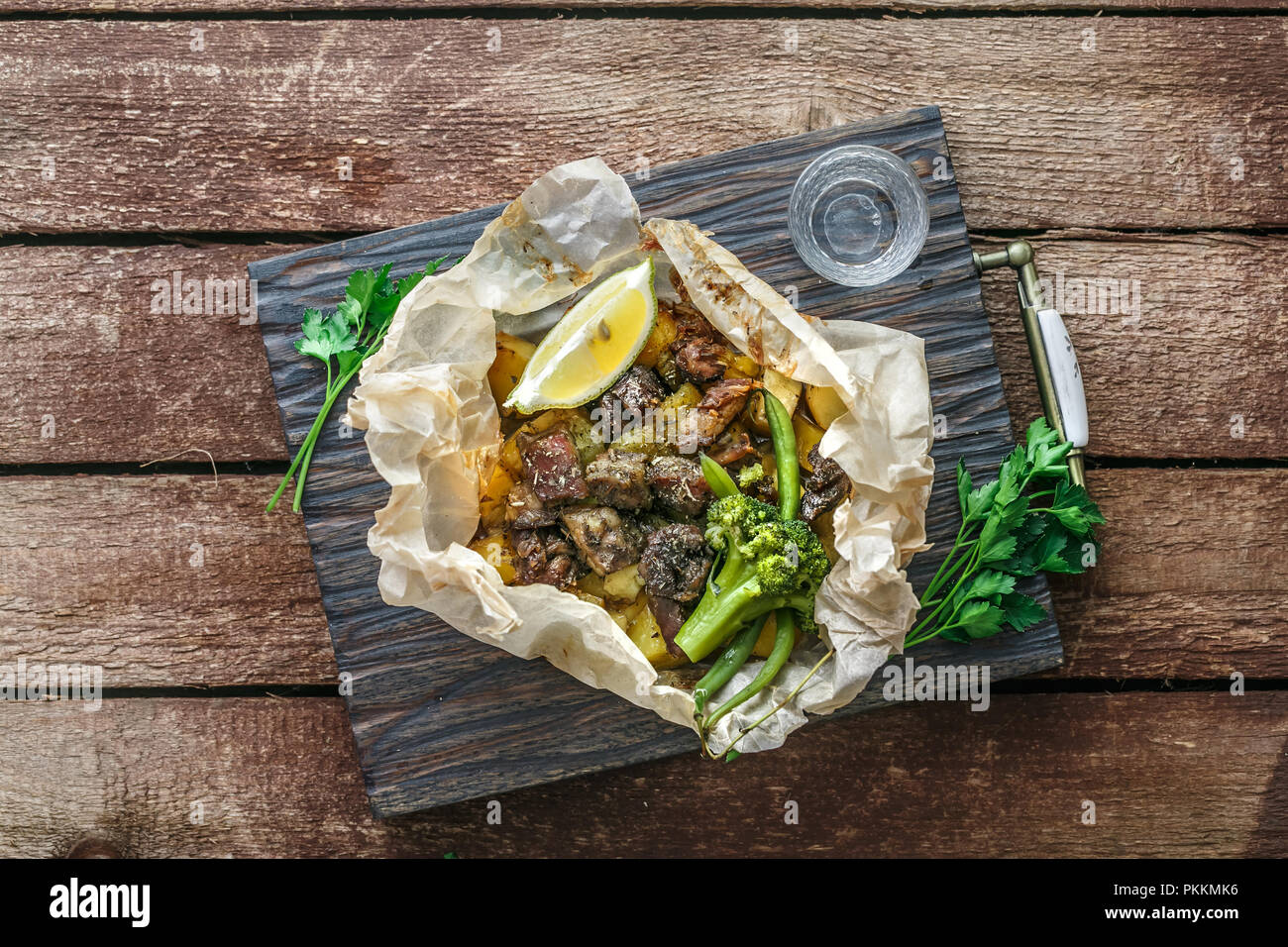 Lamm Kleftiko, Kartoffel und Gemüse auf hölzernen cutin Board serviert, rustikalen Stil. Stockfoto