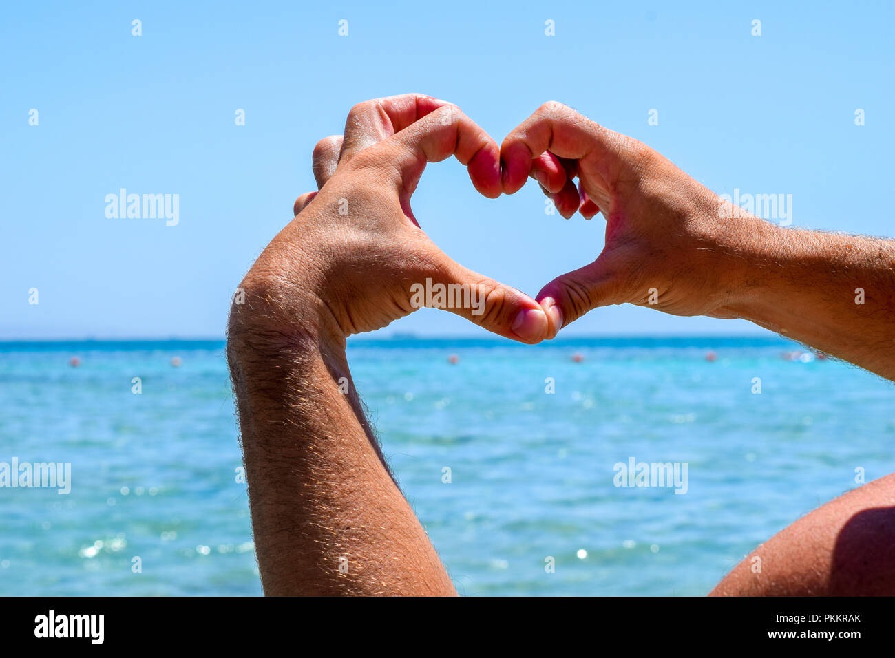 Herzform vor dem türkisfarbenen Meer mit der Hand des Menschen, der Liebe Zeichen im Paradies Stockfoto