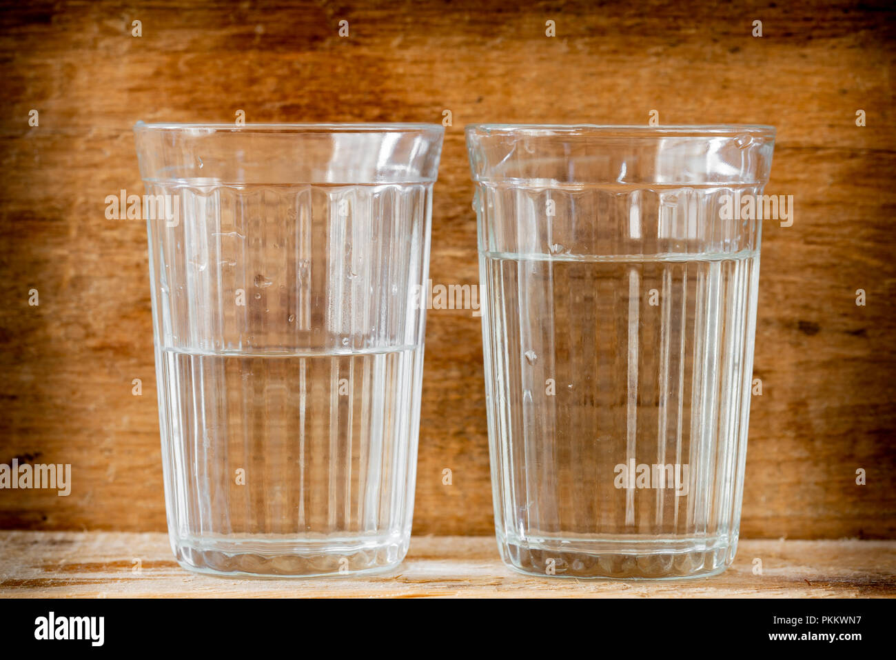 Zwei Gläser Wasser, mit natürlichem Licht beleuchtet, auf einem Holzbrett Stockfoto
