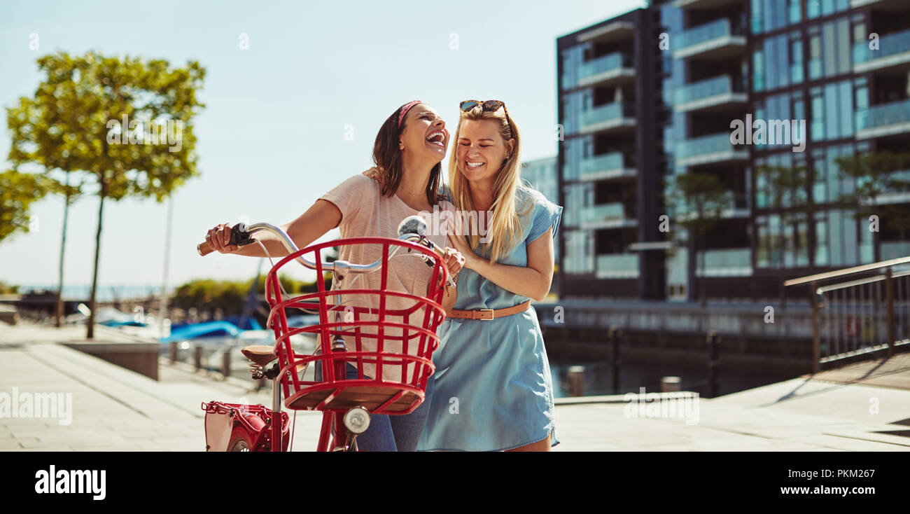 Zwei junge weibliche Freunde, die zusammen mit ihrem Fahrrad während einem Tag genießen im Sommer Stockfoto