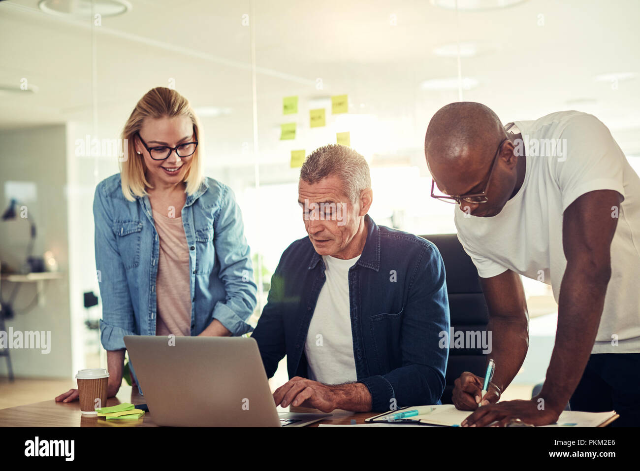 Vielfältige Gruppe von Geschäftsleuten reden über einen Laptop an einem Schreibtisch in einem modernen Büro arbeiten Stockfoto