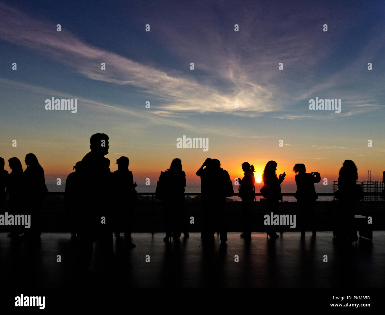 Silhouette einer Gruppe von Leuten, die eine Erholung während eines Kongresses mit dem Sonnenuntergang im Hintergrund mehrere von ihnen Aufnehmen von Bildern mit der Zelle Telefone Stockfoto