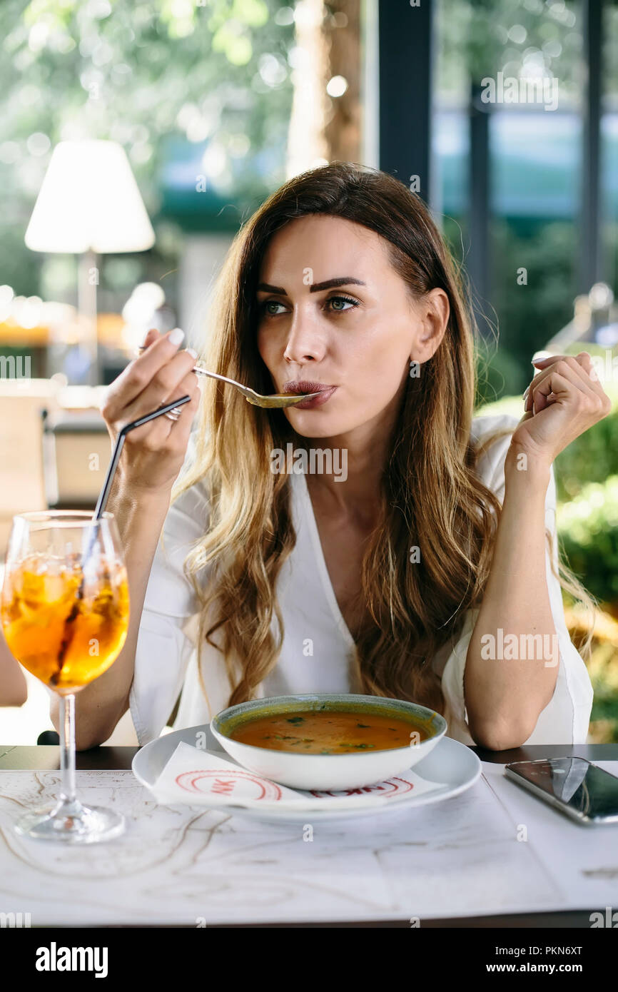 Junge attraktive Frau essen Suppe im Restaurant Stockfoto