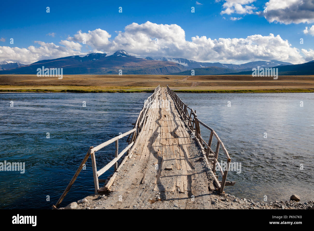 Schäbig hölzerne Brücke über einen Fluss mit weit entfernten Bergkette im Hintergrund, Altai Gebirge, der westlichen Mongolei Stockfoto