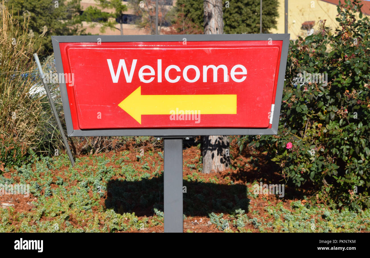 Red Willkommen Schild mit gelber Pfeil nach links Stockfoto