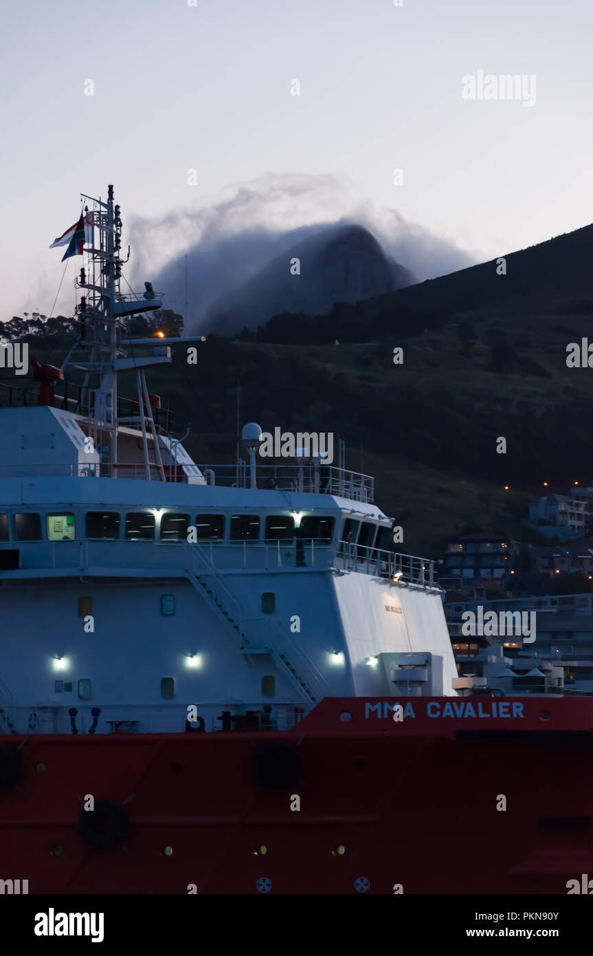 Der MMA Cavalier, ein offshore Schiff zur Versorgung bei Nacht mit Signal Hill dahinter in den Hafen von Kapstadt, Südafrika Stockfoto