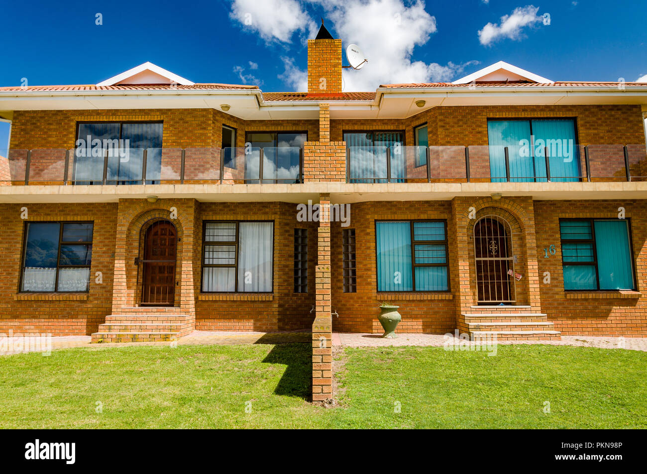Orange brick stark moderne Häuser mit Gras rasen in Mossel Bay, Südafrika Stockfoto