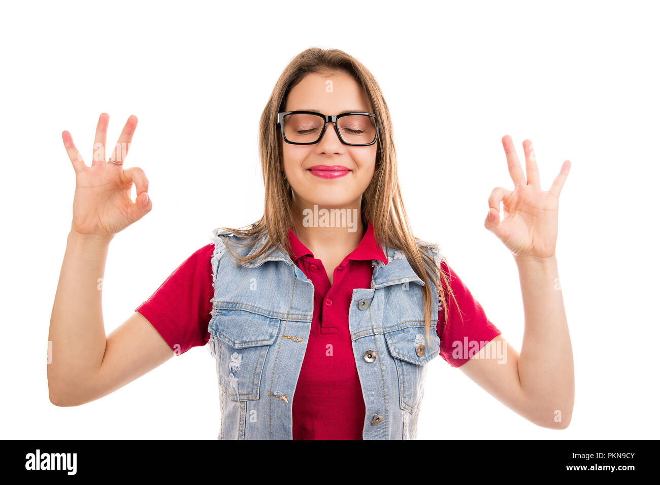 Junge ruhige Frau glücklich lächelnd, während mit den Händen bis Meditation Übersicht OK Geste auf weißem Hintergrund Stockfoto