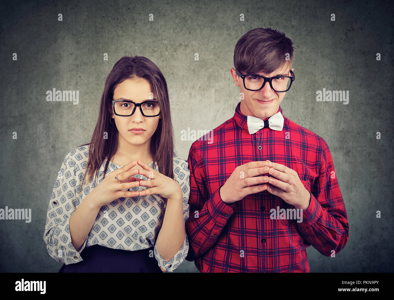 Junge böse ausdrucksvolle Paar an der Kamera während der Planung Rache und Betrug auf grauem Hintergrund Stockfoto