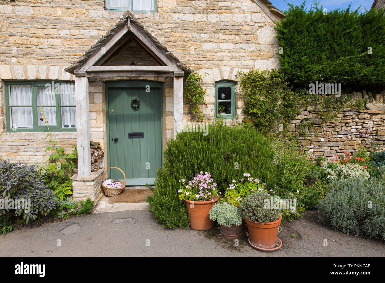 Die Tür und Fassade eines traditionellen Steinhaus in dem malerischen Dorf Lower Slaughter in den Cotswolds, UK. Stockfoto