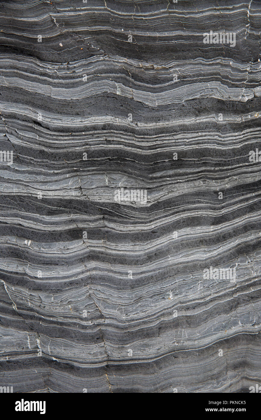 Ein Geologie Hintergrundbild von Schichten von Schiefer und Marmor Stein, die sich über Millionen von Jahren in eine Klippe Felsformation komprimiert wurden. Stockfoto