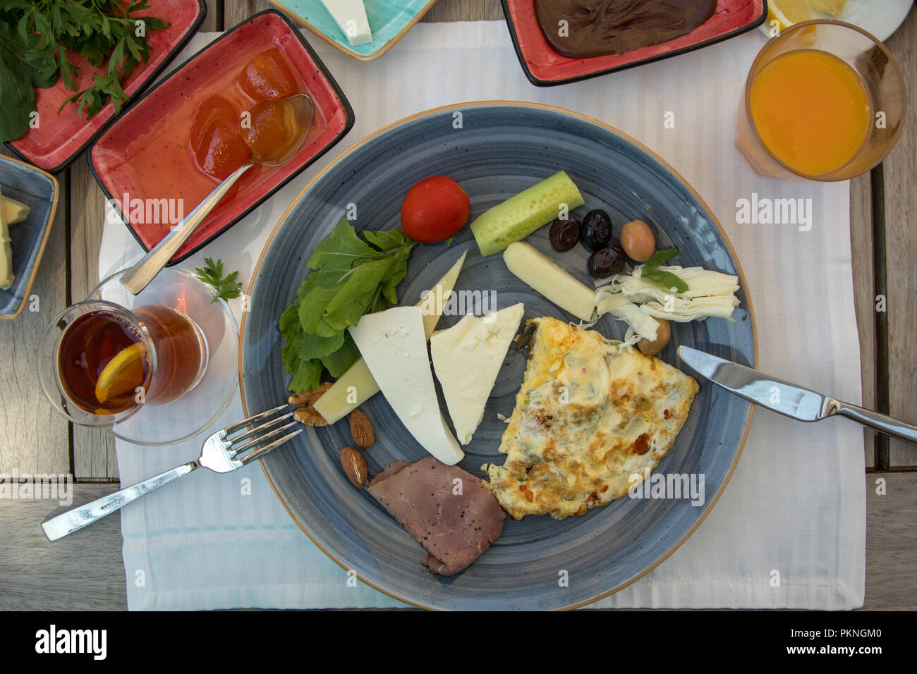 Das Frühstück vorbereitet auf Holztisch, Käse, Marmelade, Tomaten, Gurken, geräuchertes Fleisch, Butter, Honig, Oliven, Brot Stockfoto