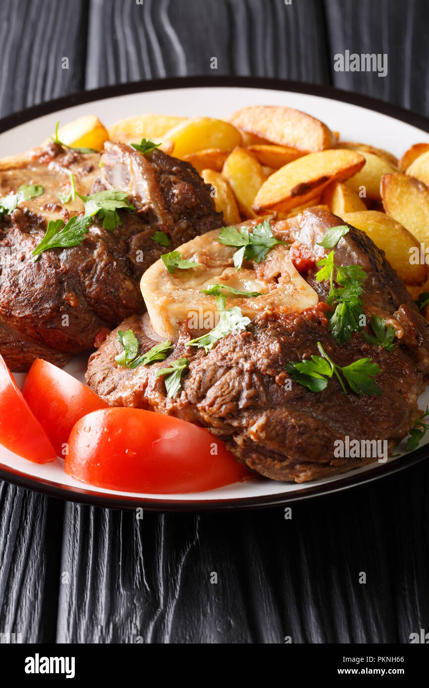 Italienisches Menu Geschmortem Kalbfleisch Ossobuco Steak Mit Bratkartoffeln Und Tomaten Close Up Auf Einem Teller Auf Den Tisch Vertikale Stockfotografie Alamy