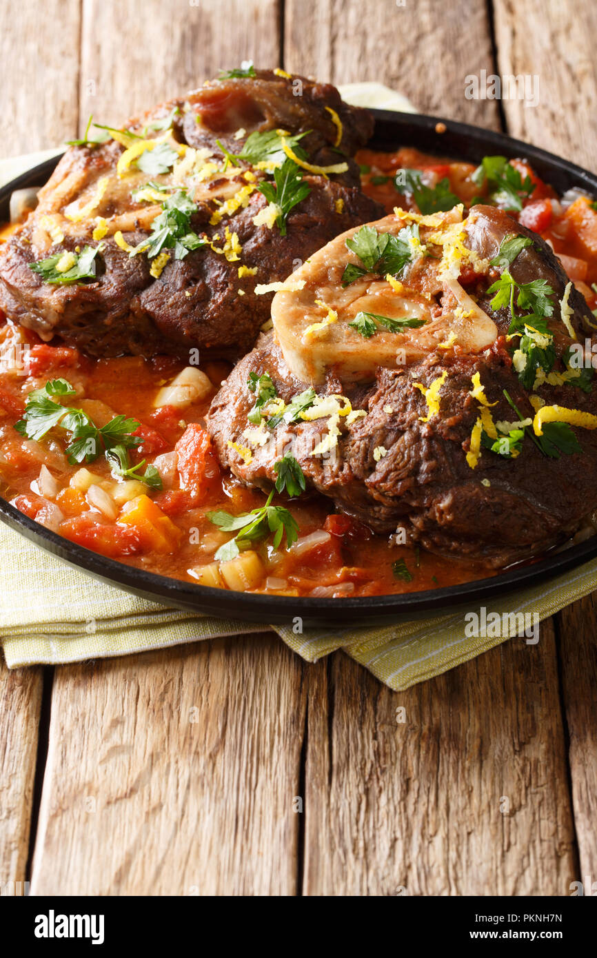 Italienische Kalbssteak Ossobuco alla milanese mit pikanter Sauce close-up auf dem Tisch. Vertikale Stockfoto